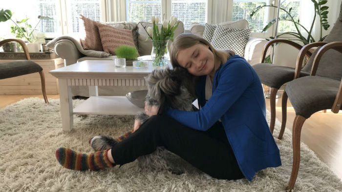 Aava from Finland sits at home with her dog