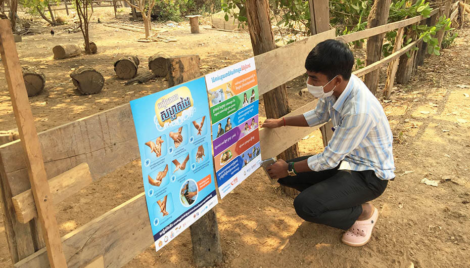 Putting up posters in rural community of Cambodia on preventing the spread of COVID-19