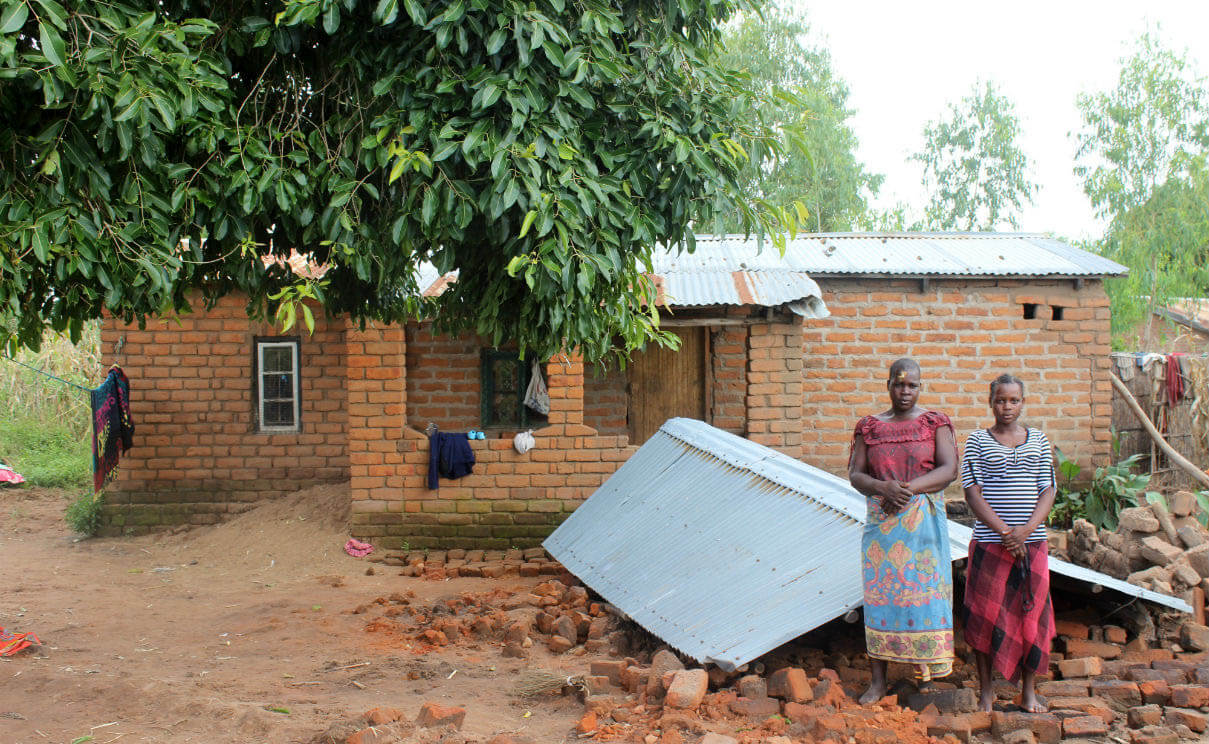 Catherine, 39, and her daughter Alindine, 17, in front of their collapsed house in Malawi