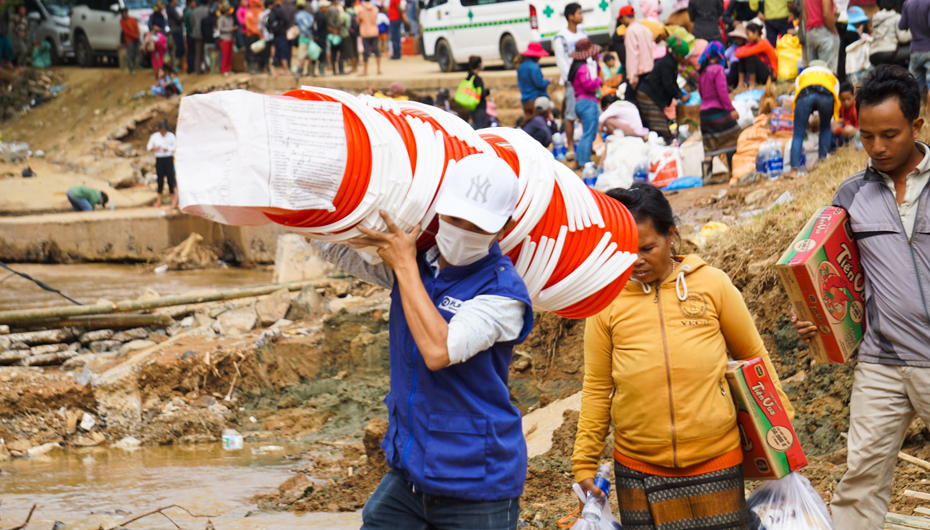 Plan Internatinoal staff member carrying relief aid over makeshift bamboo bridge in Quang Tri province