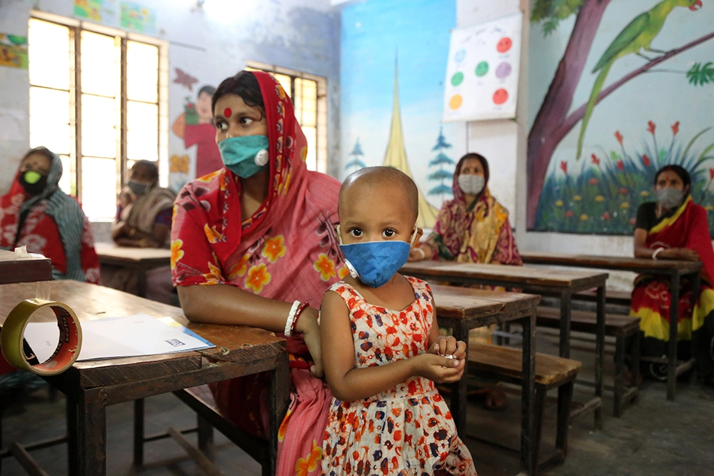 A mother and daughter wait for their cash transfer at a school in Bangladesh.