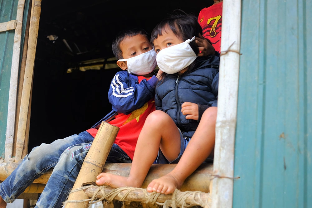 Boy helps his younger brother put on face mask in Vietnam