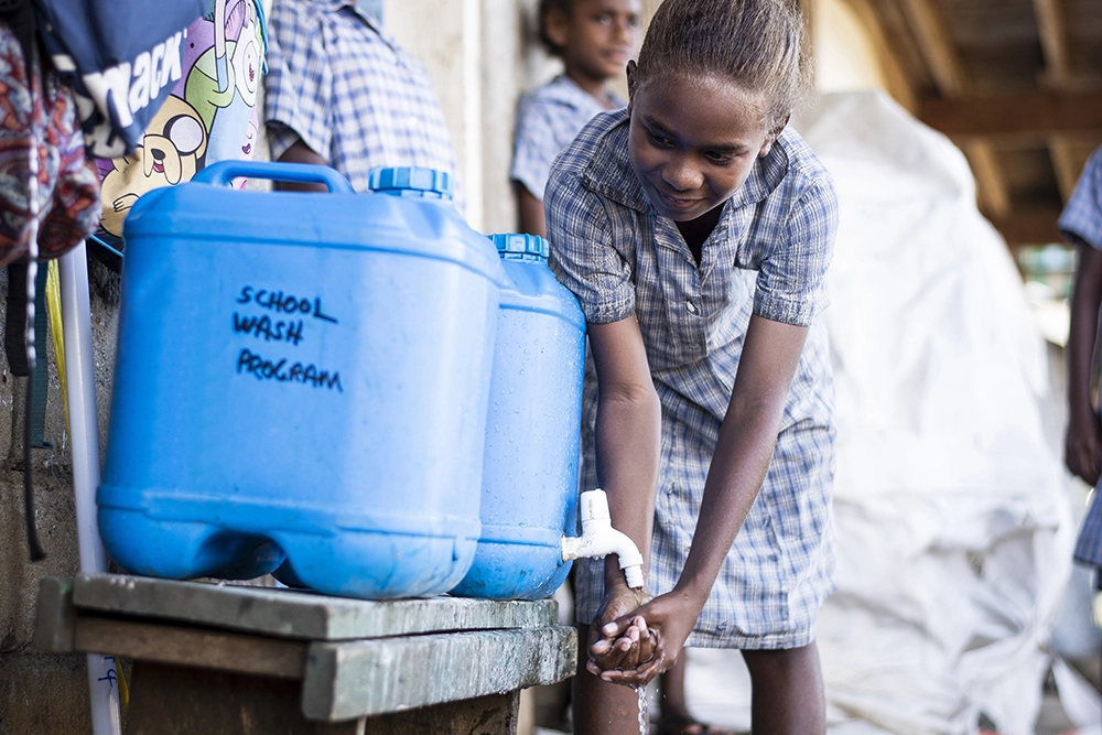 A girl washes her hands at a school in the Solomon Islands