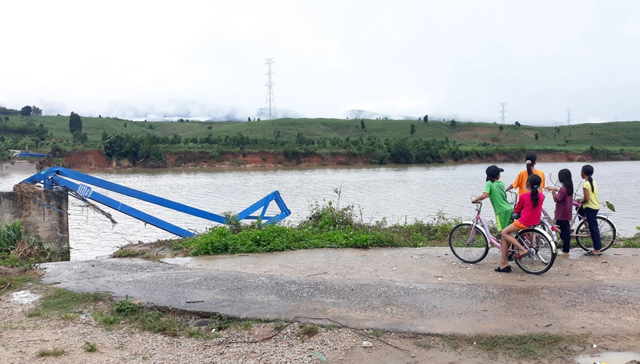 Children look at destroyed bridge preventing them from getting to school