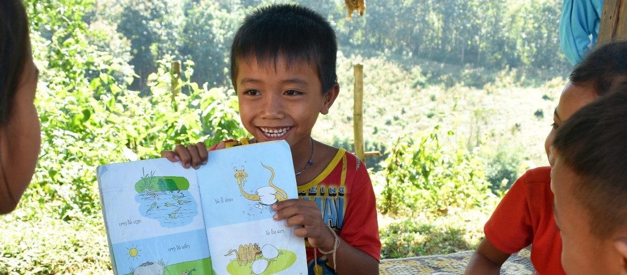 Seuk, 7, reads a storybook to his friends at the reading club