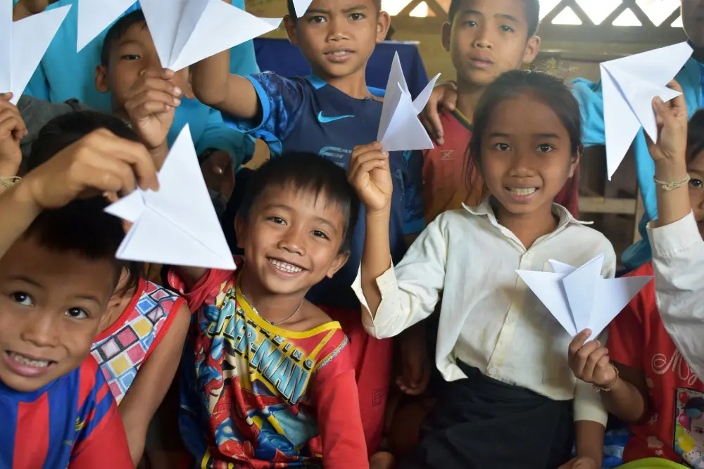 Seuk, (middle) 7, and his friends show off their paper aeroplanes made at the reading club 