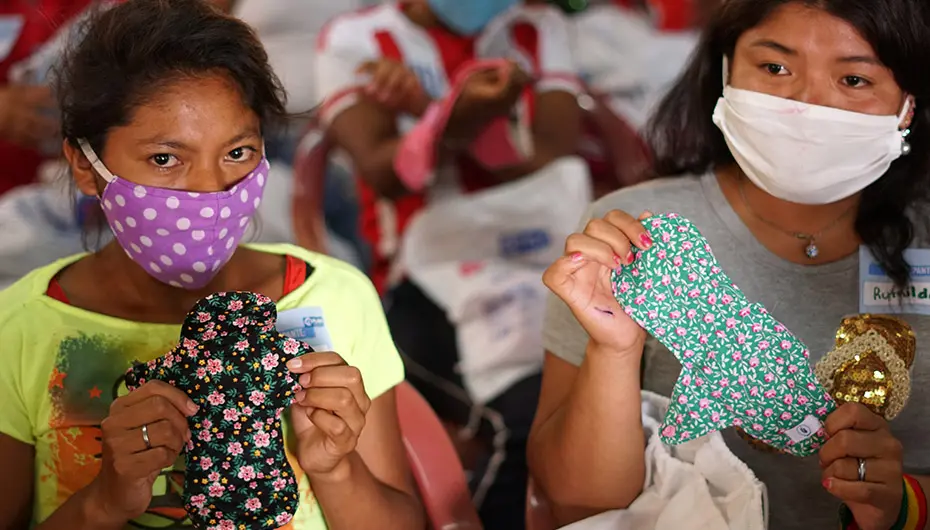 Young women learn how to use the reusable sanitary pads during training session