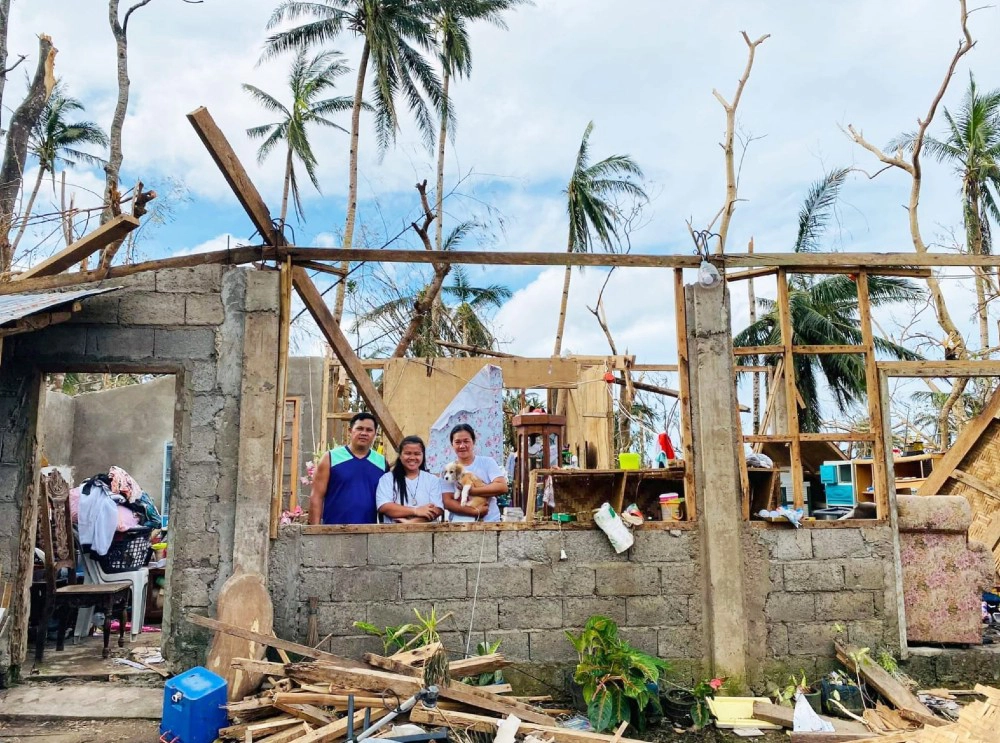 Francine, 15, with her parents and pet dog Snow in their ruined home