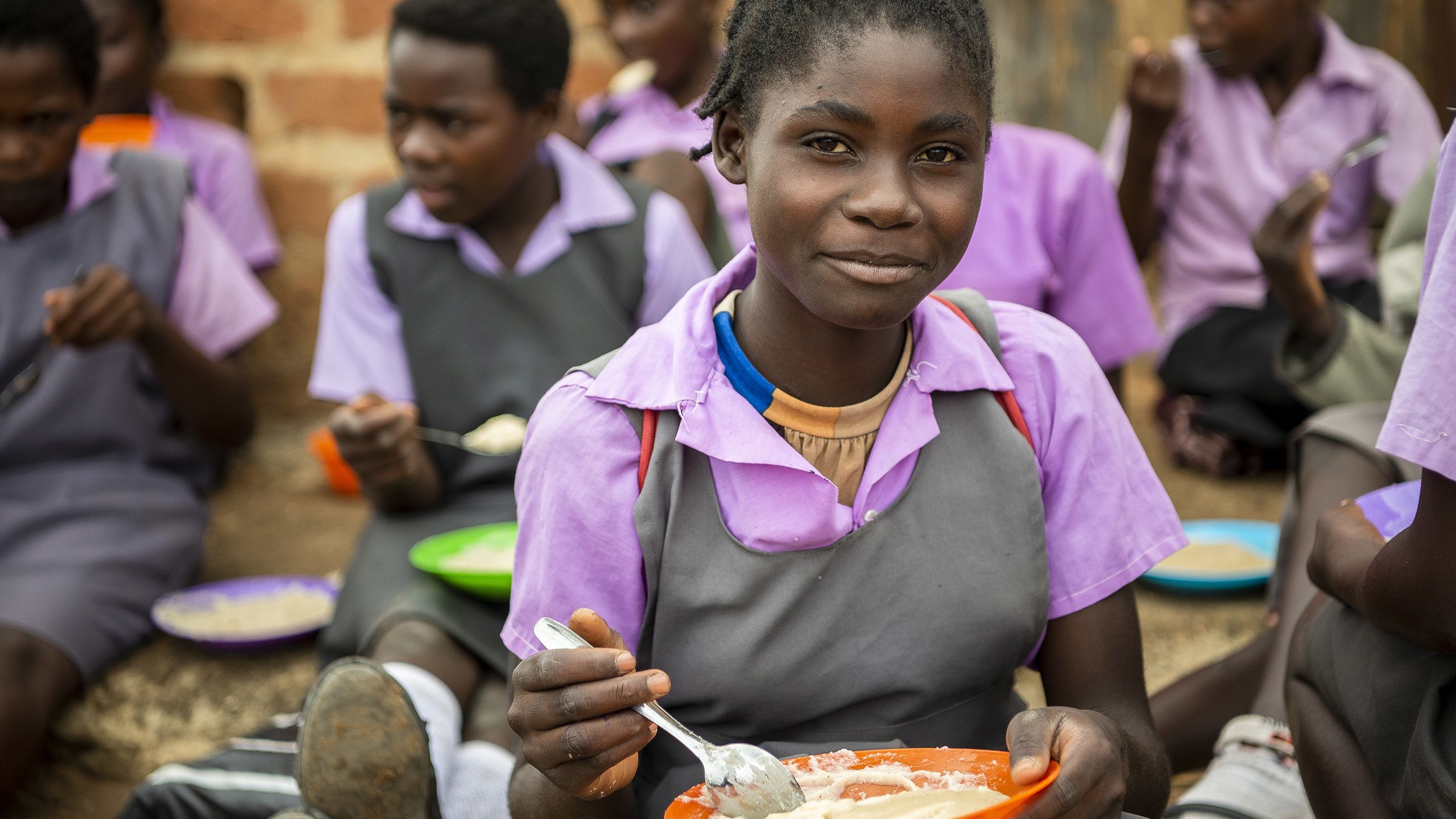 Young female student eats a meal prepared as part of school feeding program