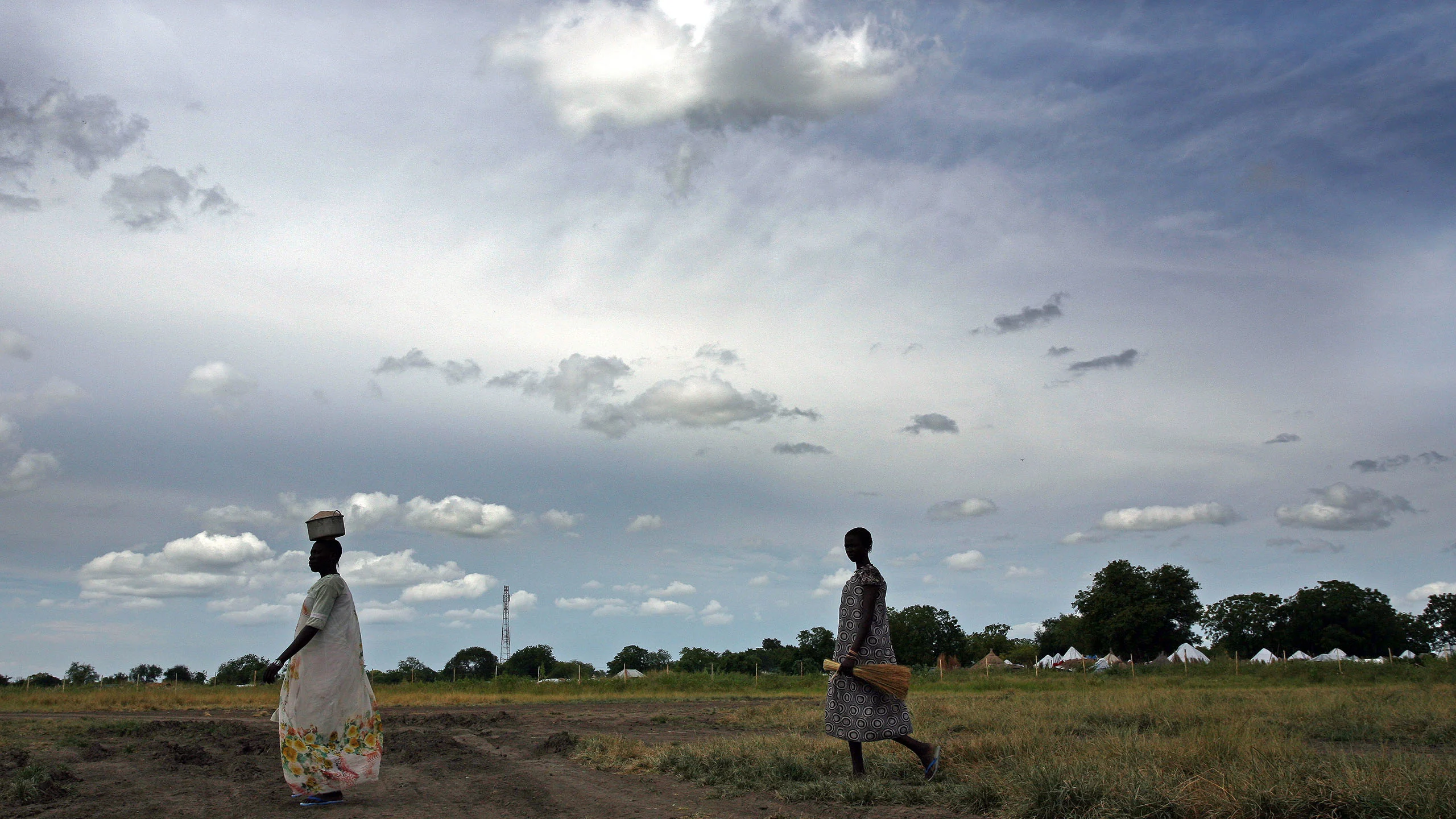 Women walk across an open field.