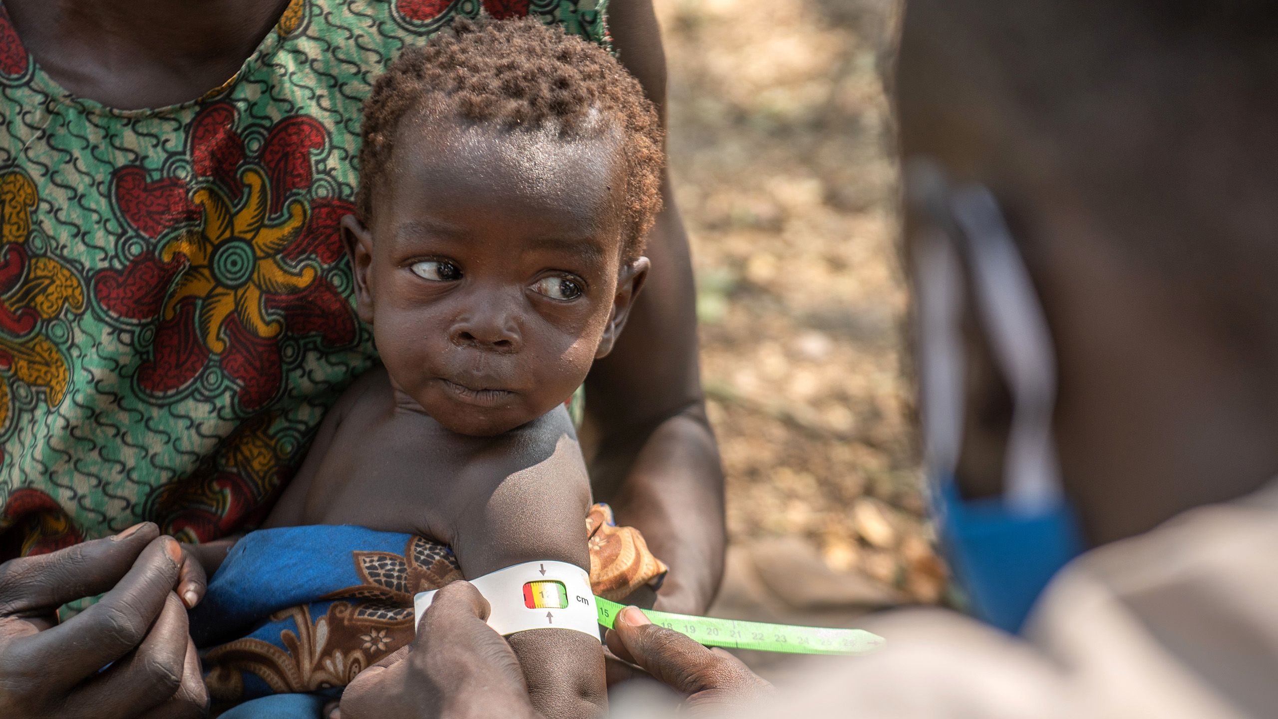 Child is measured for malnutrition while held by mother.