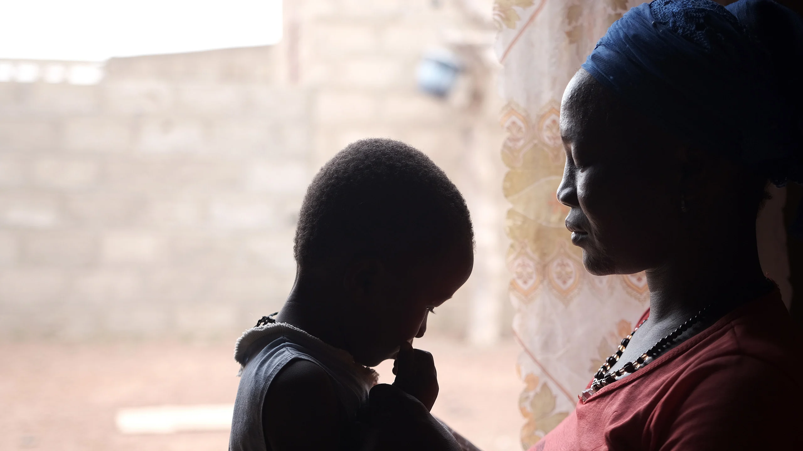Young girl is held by her mother in a doorway.