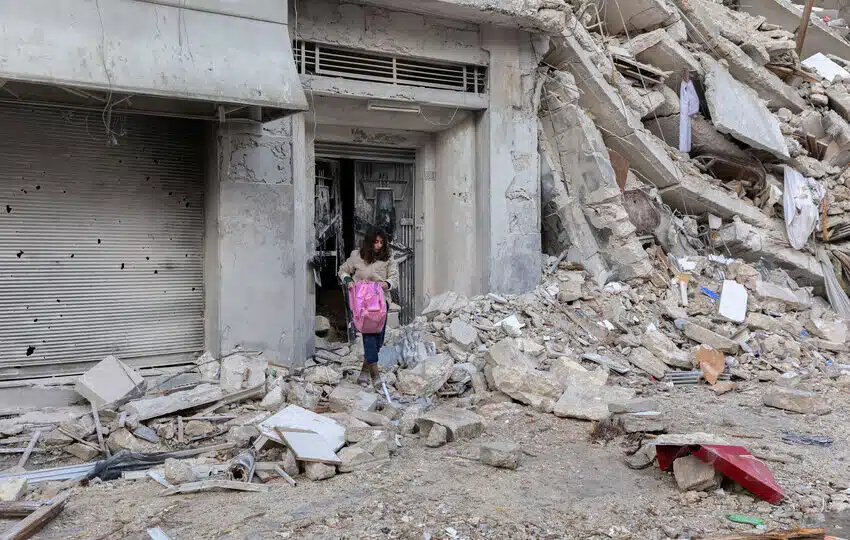Woman salvages some possession from badly damaged building in Aleppo, Syria