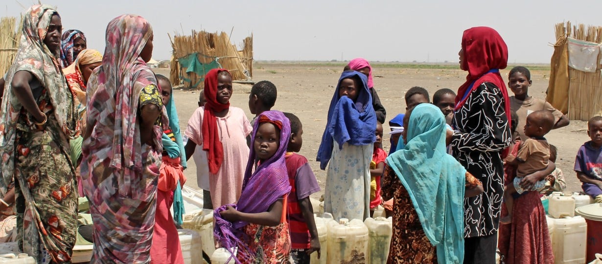 Women and children from Sudan collect water from water point in IDP camp