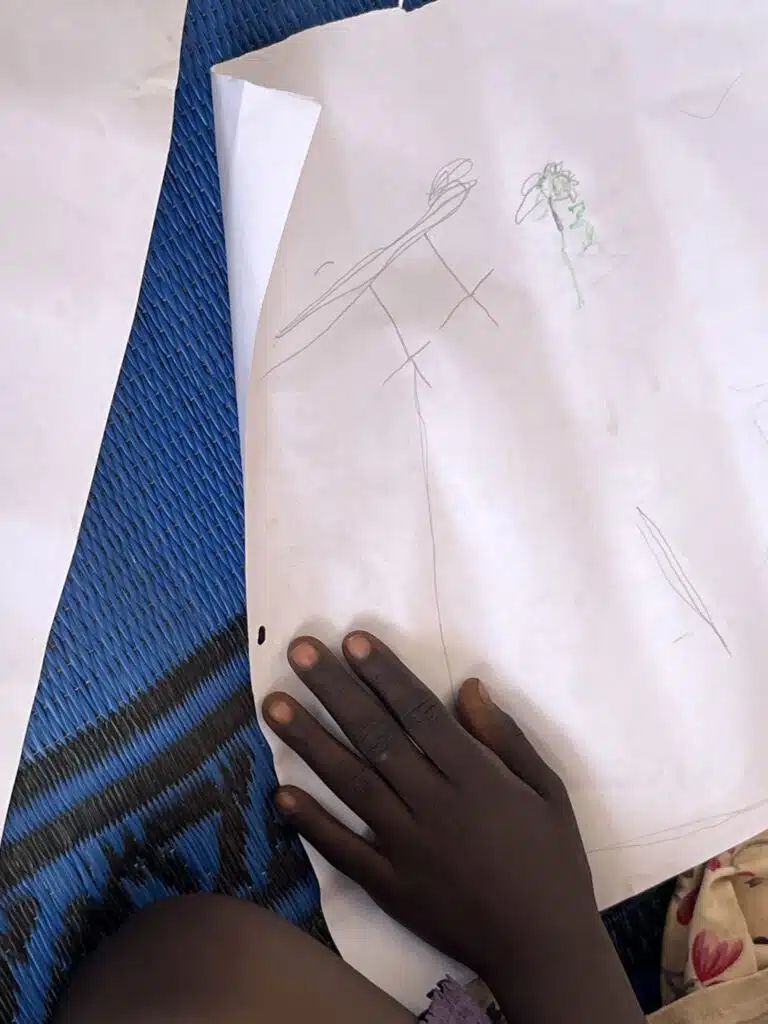 Lamia*, 4, draws a kite at a child-friendly space in a refugee camp