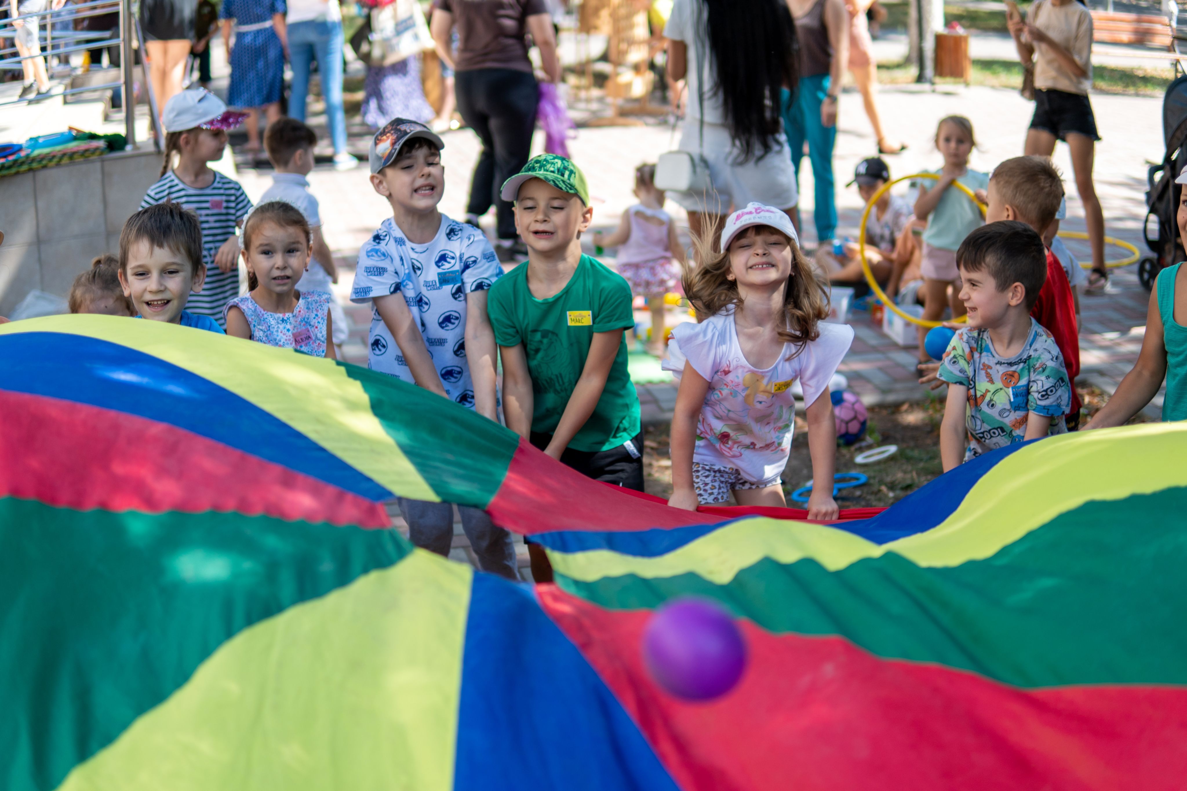 Children play with colourful parachute at Ludobus play session in Moldova.