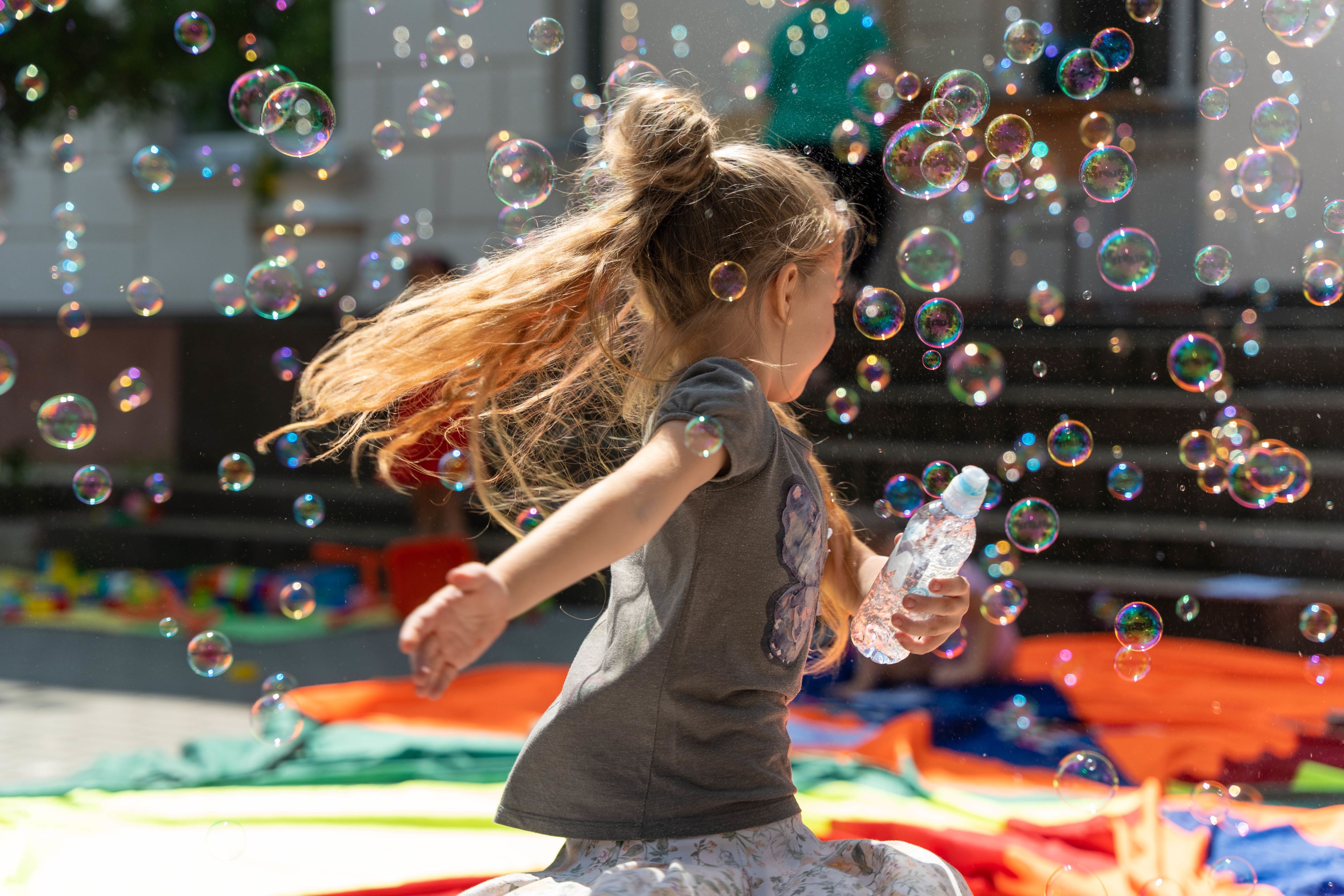 Girl enjoys playing with bubbles at the Ludobus play session.