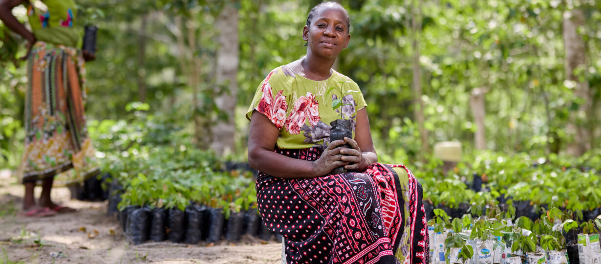 Community leader, Caroline Kiti is writing a new chapter for Kenya’s forests – one seedling at a time. Through tree planting, Caroline is helping rebuild a section of the sacred Mijikenda Kaya Forests in Kenya, with help from Plan International’s Conservation and Sustainable Management of Coastal and Marine Ecosystems (COSME) project. 

As chairperson of a local conservation group, Tumaini (meaning “hope”), Caroline leads efforts to balance preservation with community needs. The group has planted 5,000 indigenous seedlings, including traditional medicinal trees. For Caroline, her other significant achievement is the role she plays in her community in bridging gender divides. While Tumaini started as a women’s conservation group, it has evolved into a community-wide movement.

“We’re the freedom fighters of clean air and good medicine,” Caroline declares, her commitment to Kaya Chonyi unwavering. In her hands, she holds milk bags salvaged from roadsides, recycled into seedling containers to cradle the next generation of trees – a testament to how traditional wisdom and modern conservation can nurture both forest and community.