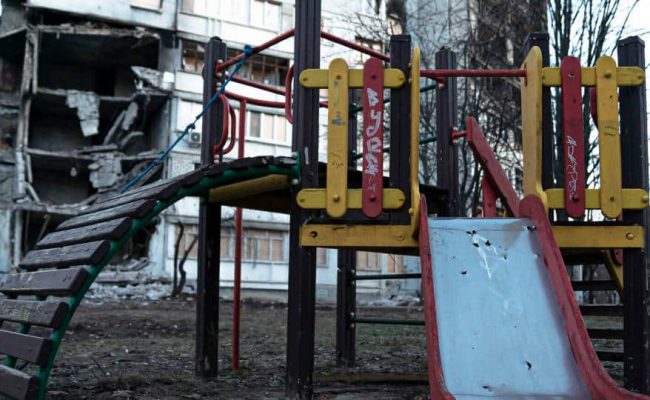 Children's playground against backdrop of bomb damaged buildings